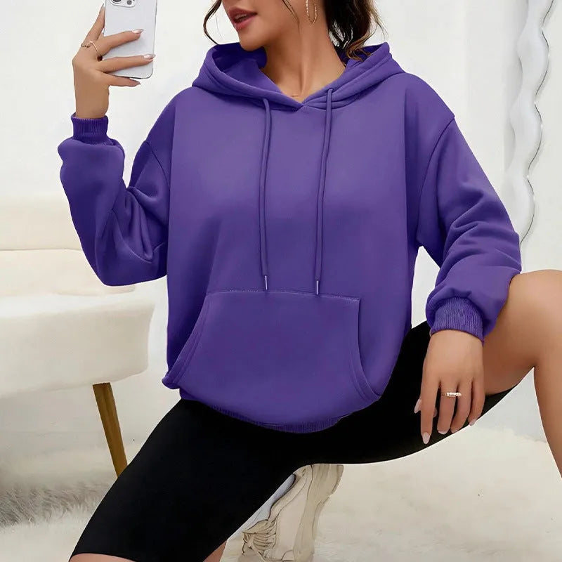 Women's loose fit grey hooded sweatshirt with front pocket and long sleeves on a hanger.