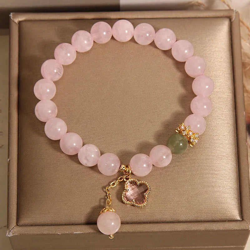 Pink women's bracelet with a crystal four-leaf clover pendant and rhinestone details on an adjustable chain.