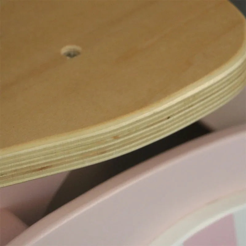 Pink wooden balance scooter for toddlers, 10 inches in size, on a flat surface.