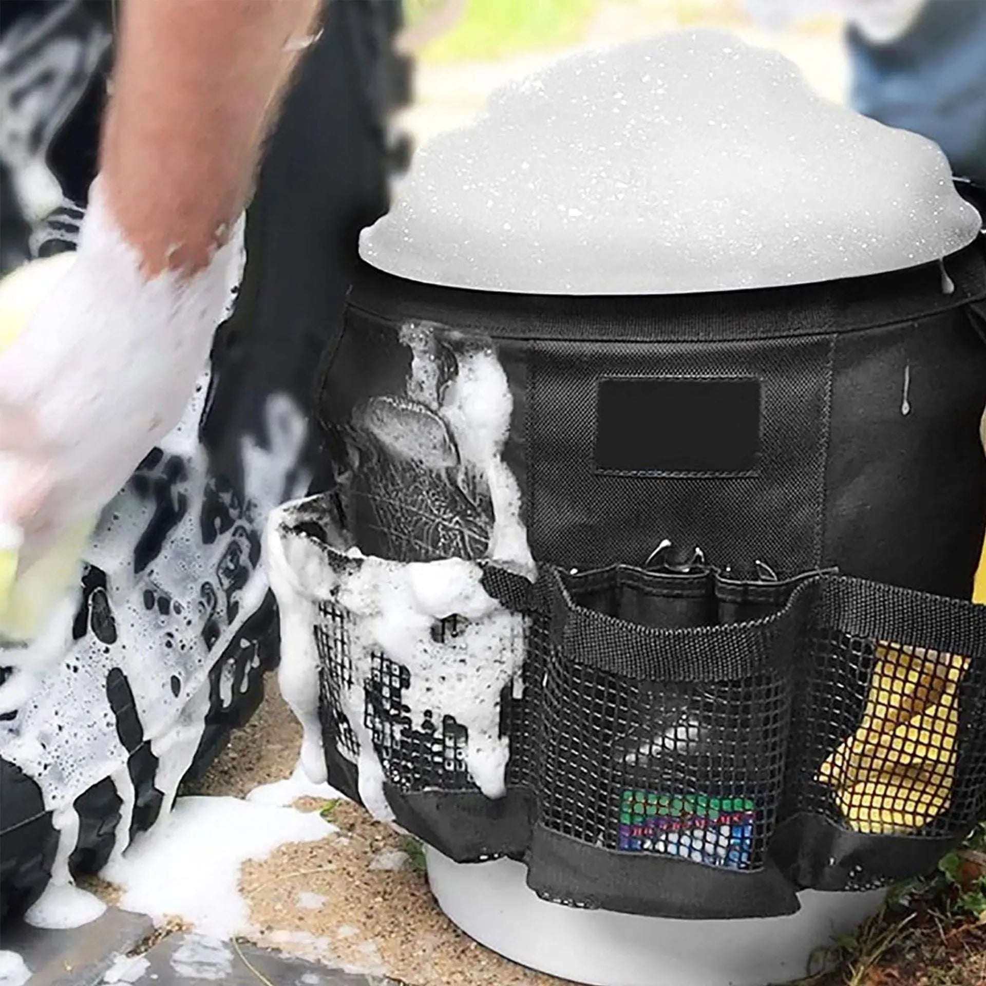 Black cylindrical polyester storage bag with straps hanging from a 5 gallon bucket.