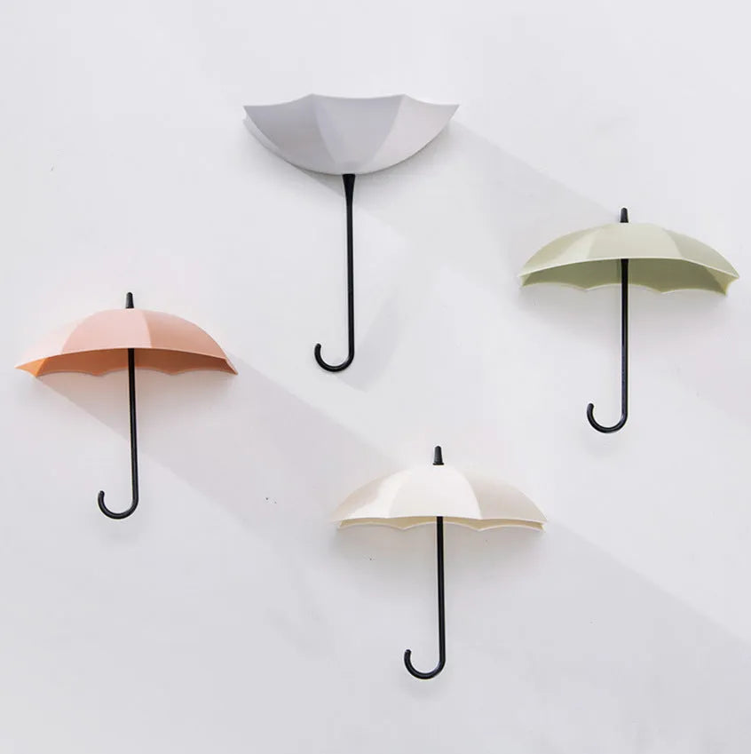 3 plastic umbrella-shaped sticky hooks in Nordic pink blue green, on a white door, holding keys