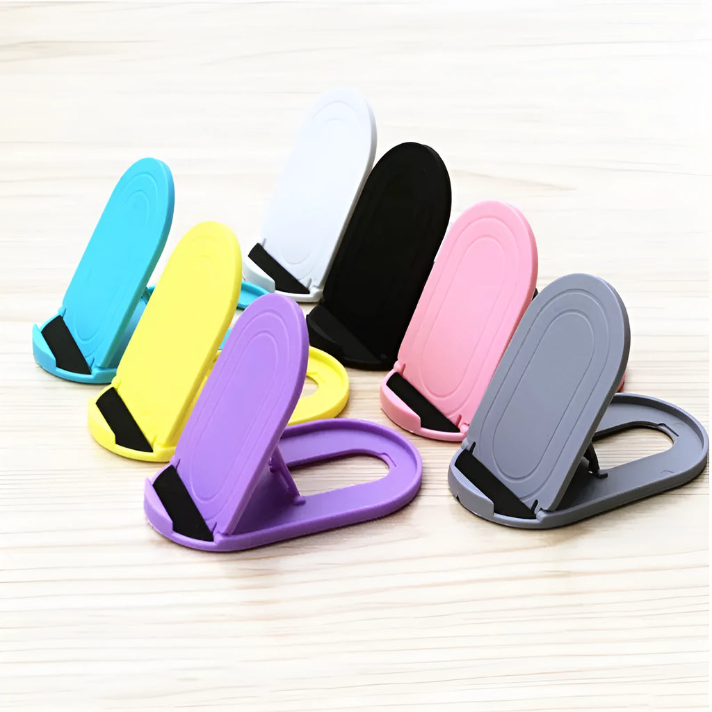 Plastic lazy bracket mobile phone stand on a desk, shown in assorted colours including black, blue, and pink.