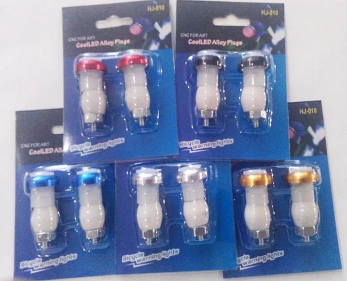 A pair of anodised aluminium bicycle handlebar end lights in a choice of colours, showing the red LED and white rubber switch.