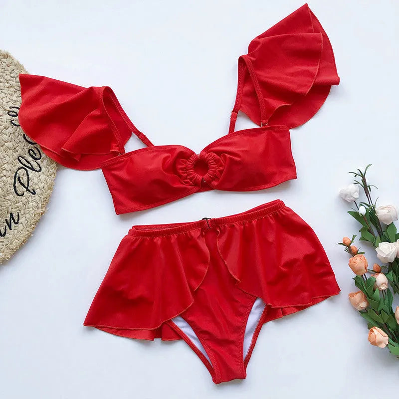 Women's red and black three-piece flounced bikini swimsuit on a hanger.