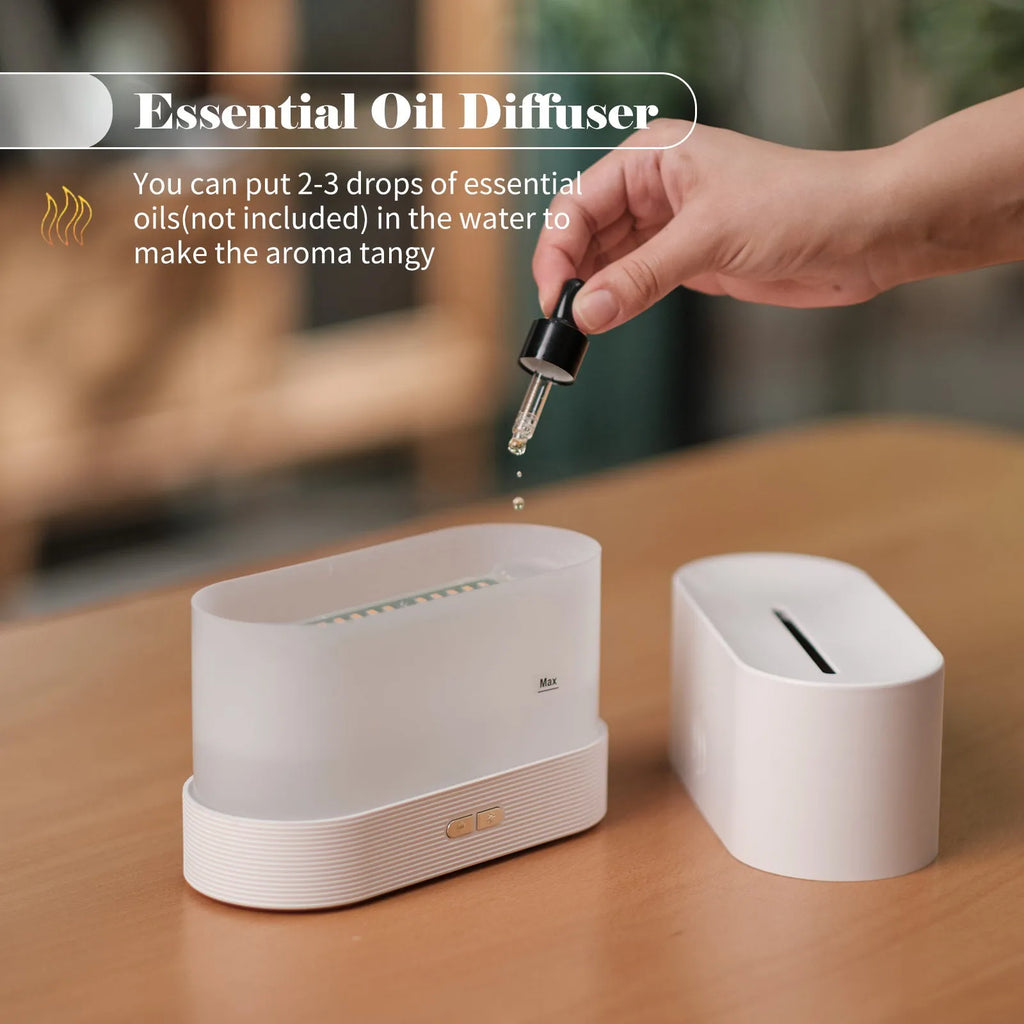 Square black ultrasonic aroma diffuser with flame light effect and water tank on a wooden table.