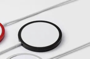 Silver metallic Magsafe magnetic wireless charger for iPhone on a wooden desk.
