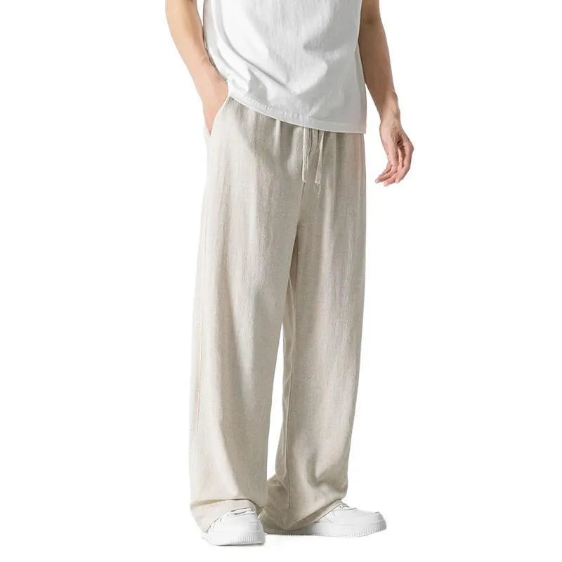 Man wearing beige loose-fit straight-leg cropped trousers with a drawstring waist.