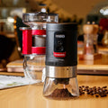 Black portable hand crank coffee grinder with manual grinding mechanism on counter