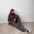 Women's dark grey knit co-ord suit with side-slit sweater top and matching trousers.