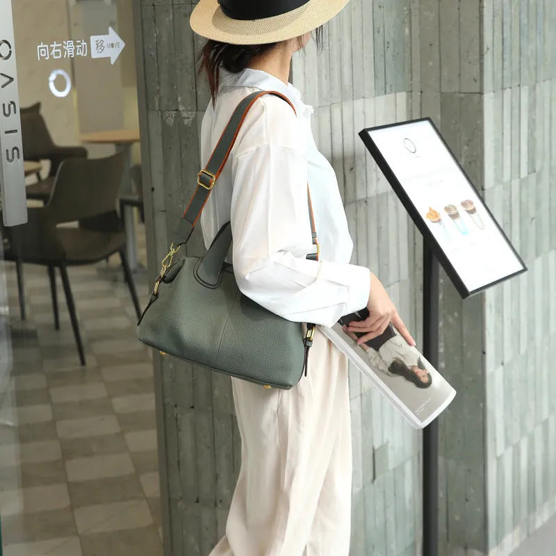 Women's leather cross-body bag in horizontal square shape with visible sewing thread detailing and interior compartments