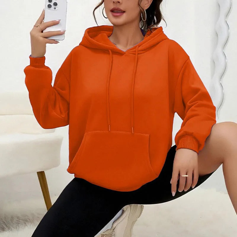 Women's loose fit grey hooded sweatshirt with front pocket and long sleeves on a hanger.