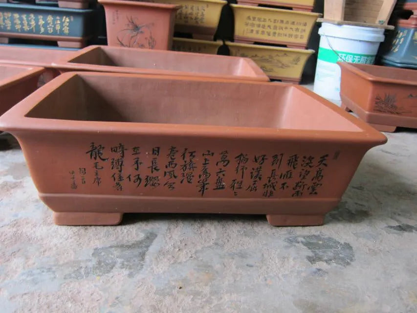 Two Yixing purple clay rectangular flower pots in different sizes on a wooden surface