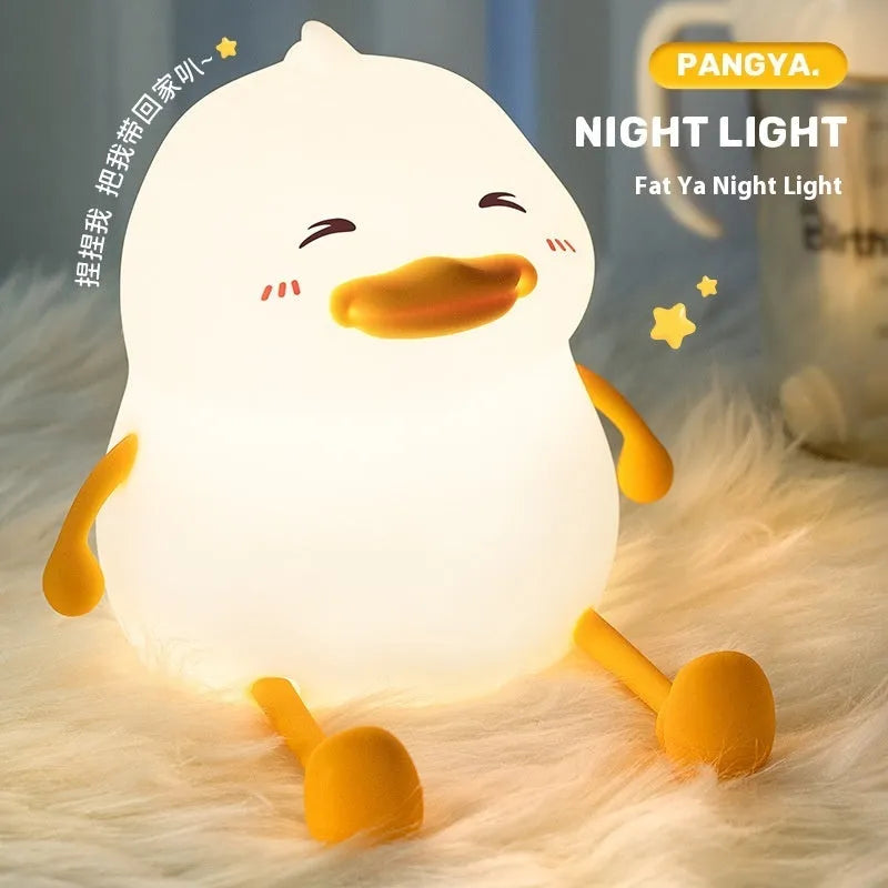 Chubby silicone pat night light on a desk showing soft LED glow and USB charging cable.