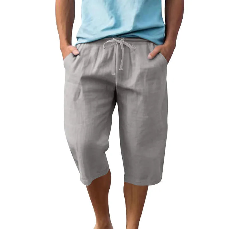 Man wearing loose, high-waisted linen shorts in a solid colour with a drawstring waist.