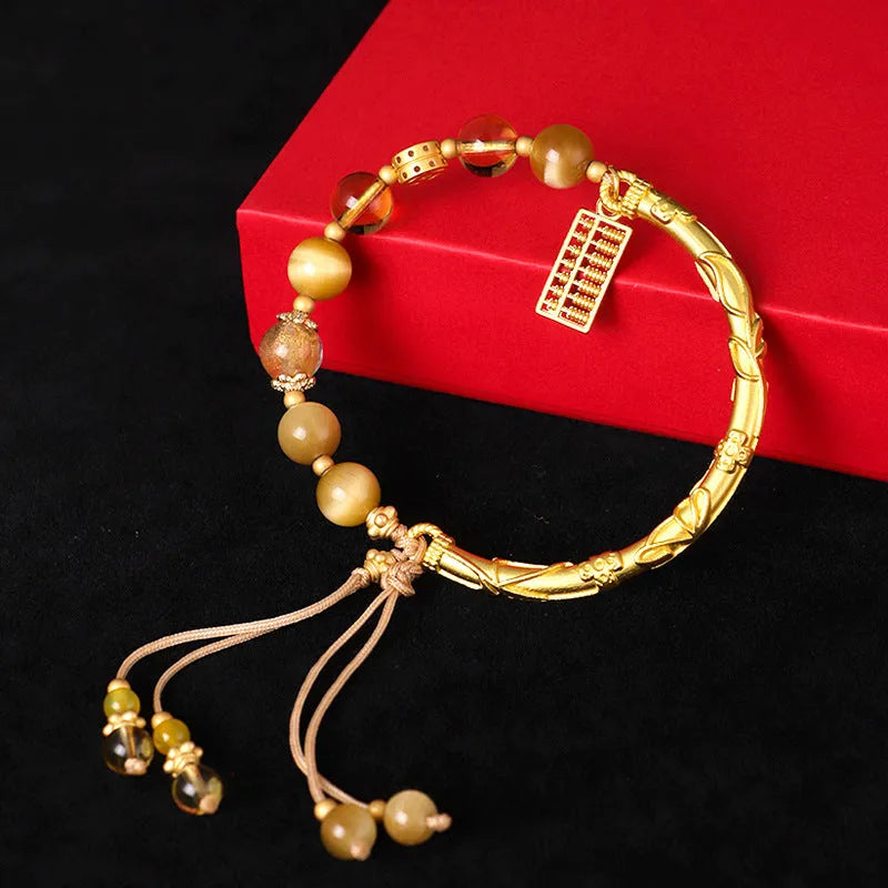 Close-up of handmade abacus bracelet with tigereye, citrine, and yellow tower crystal beads in a diamond shape on a wrist.
