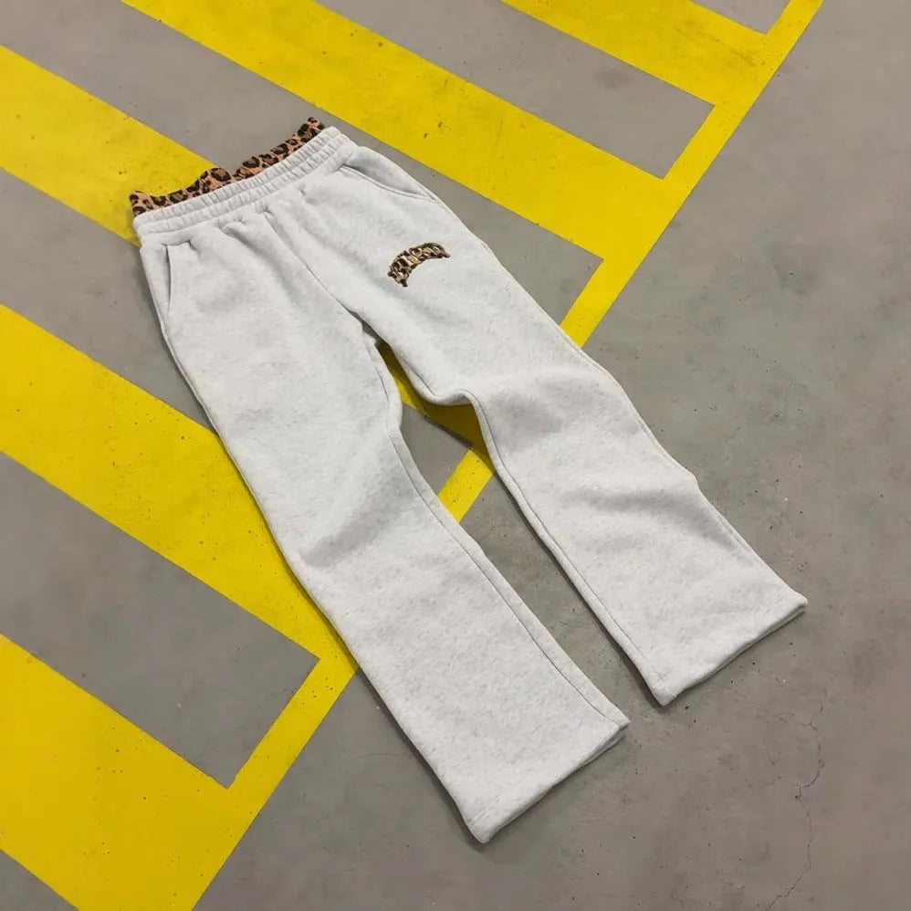 Men's loose grey hip hop trousers showing patchwork double waist detail and elastic fabric.