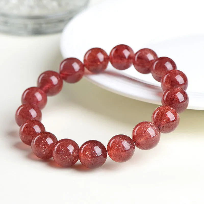 Natural cherry red strawberry quartz bracelet with geometric beads on a wrist.