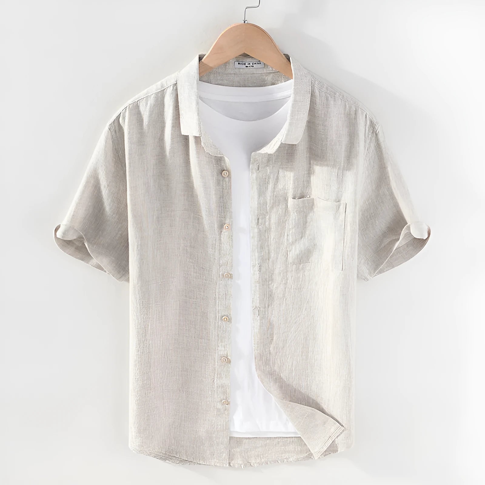 Men's raw jute colour linen shirt with square collar and short sleeves on a hanger.