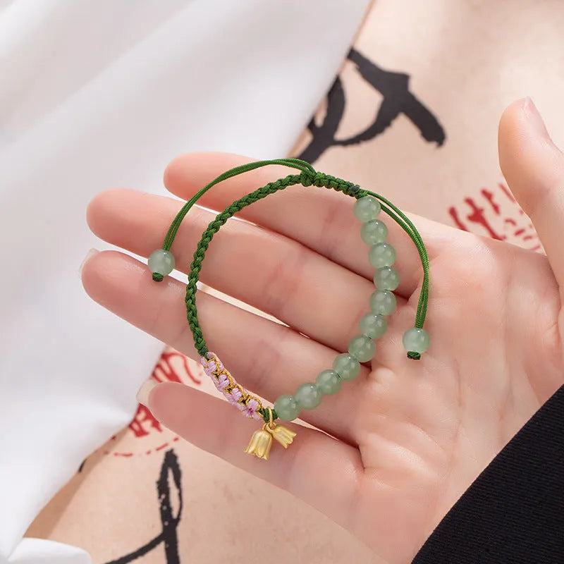 Close-up of a hand-woven red rope bracelet with floral design details on a wrist.