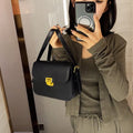 Soft black PU leather women's square cross-body bag with textured finish shown on model.
