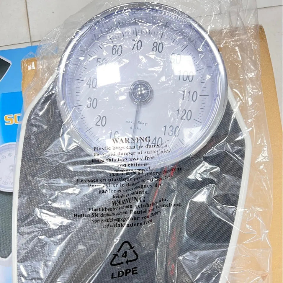 Black mechanical bathroom scale with analogue dial showing weight measurements