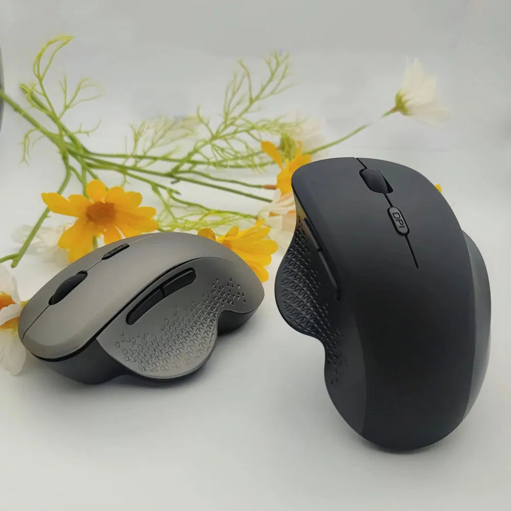 Grey wireless optical mouse with USB charging cable next to laptop computer