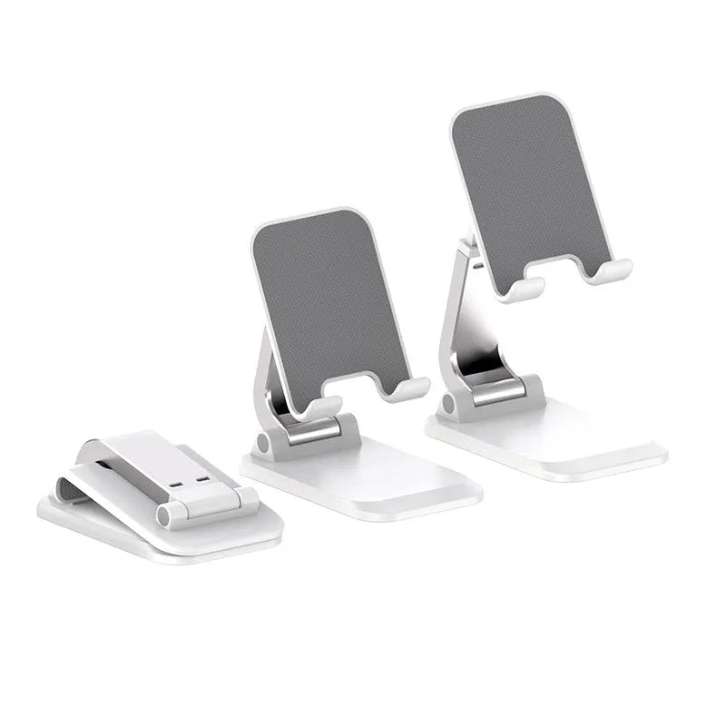 Folding portable desktop mobile phone stand in black, white, blue, or pink on a wooden desk.