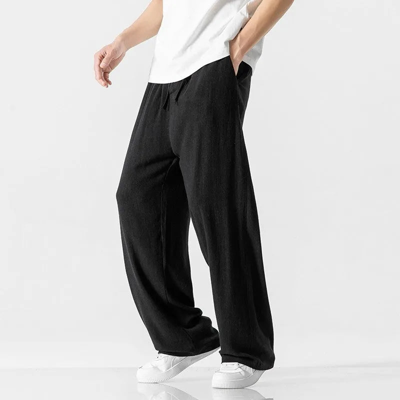 Man wearing beige loose-fit straight-leg cropped trousers with a drawstring waist.
