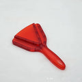 Red plastic telescopic can and bottle opener with non-slip handle on a kitchen counter.