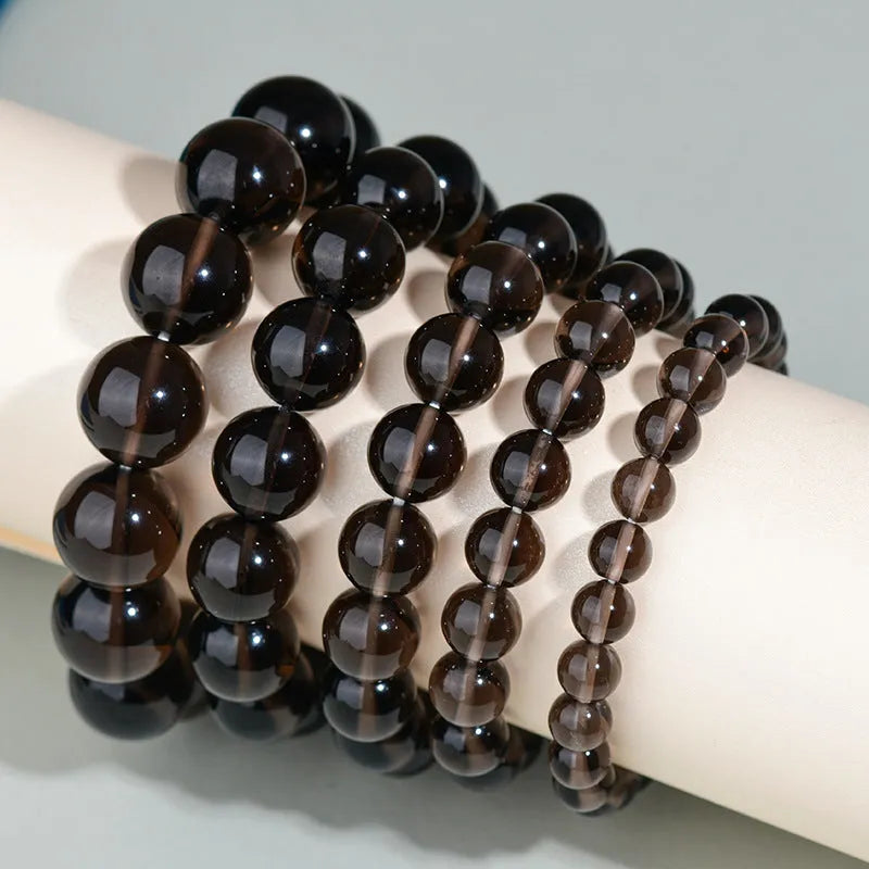Hand-woven round obsidian crystal bracelet for couples on wrist, showing ethnic style and adjustable fit.