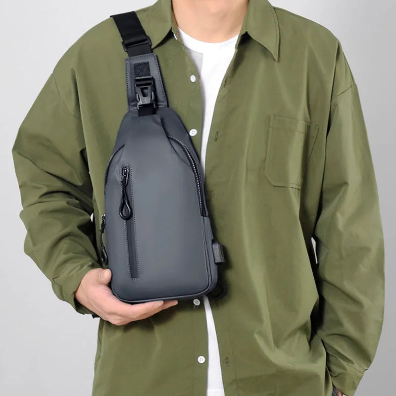 Black sling crossbody chest bag for men with zipper closure and stitched detail on a white background