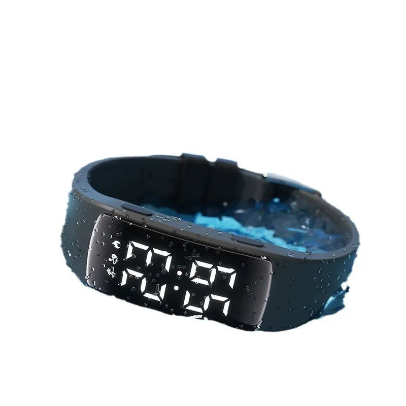Vibration alarm clock watch with LED display and coloured silicone strap on a wrist.
