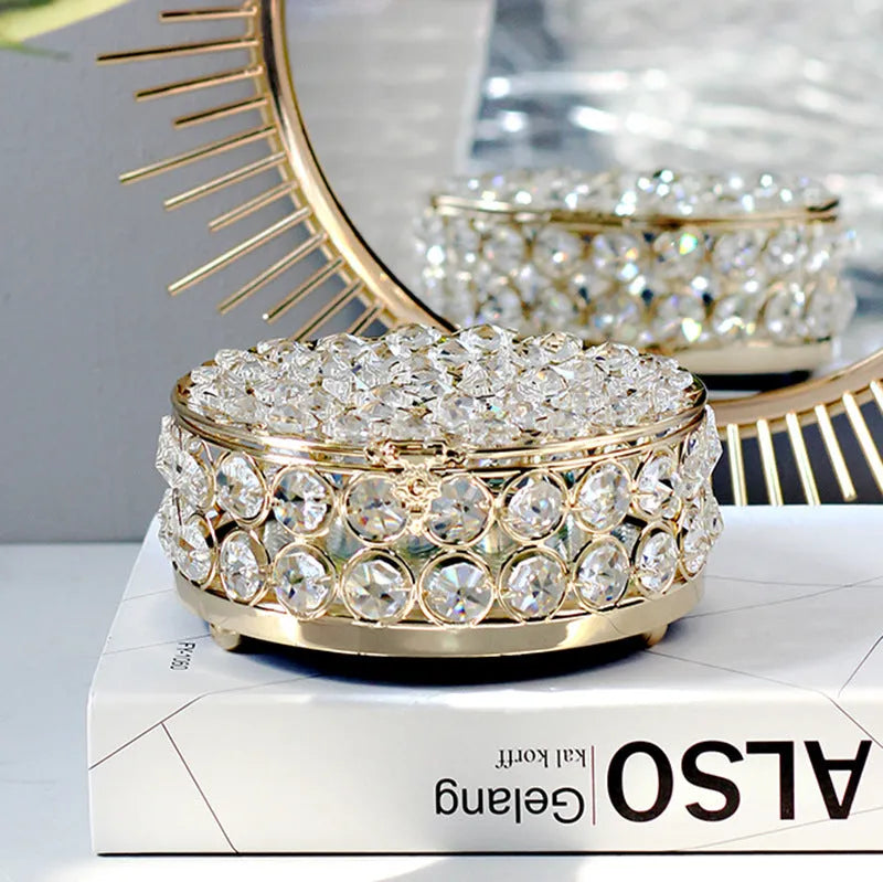 French gold iron jewelry storage box with a clear crystal glass lid on a wooden surface.