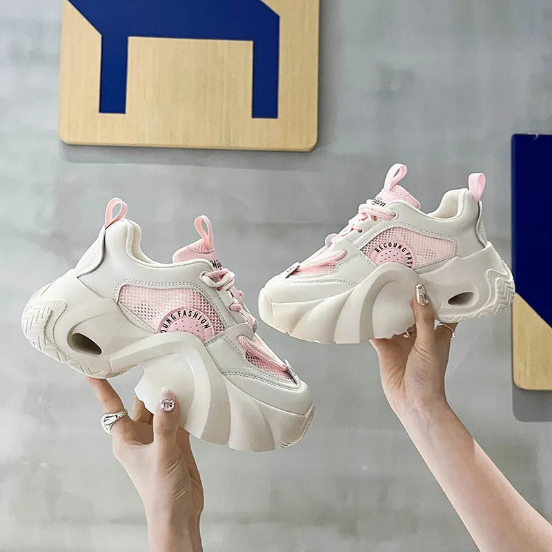 Women's pink sneakers with a thick sole, cross shoulder straps, and a mesh lining.