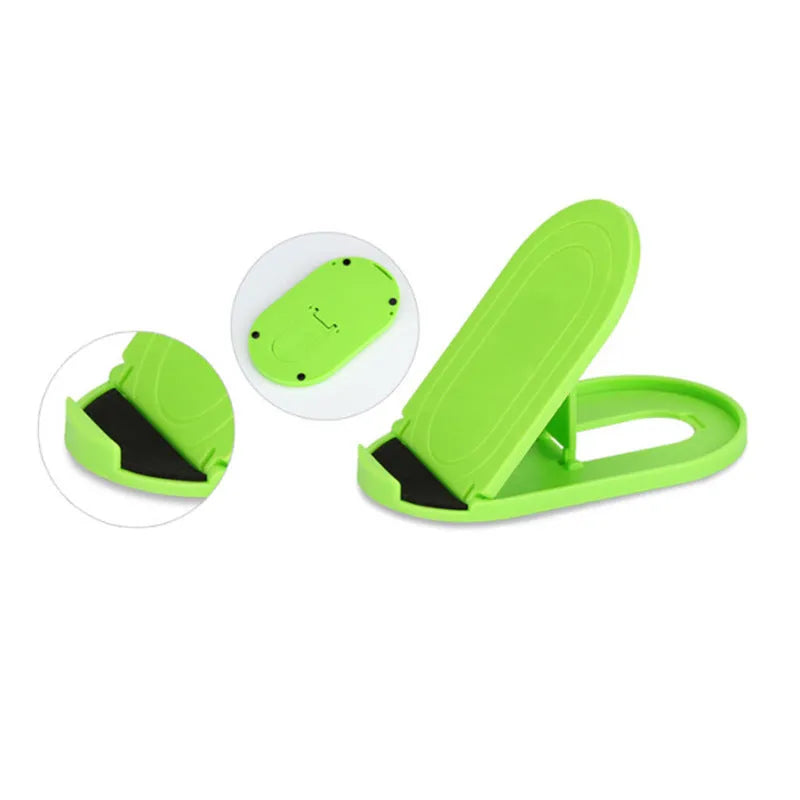 Plastic lazy bracket mobile phone stand on a desk, shown in assorted colours including black, blue, and pink.