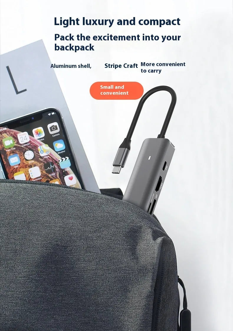 Silver aluminium 7-in-1 USB hub with SD card slot, microSD slot, USB-C PD port, and multiple USB-A ports.