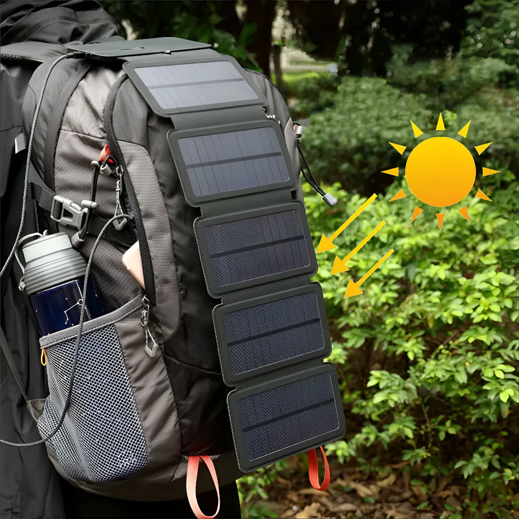 Black folding solar panel charger with monocrystalline cells and USB output, folded flat on a wooden surface, compass buckle visible