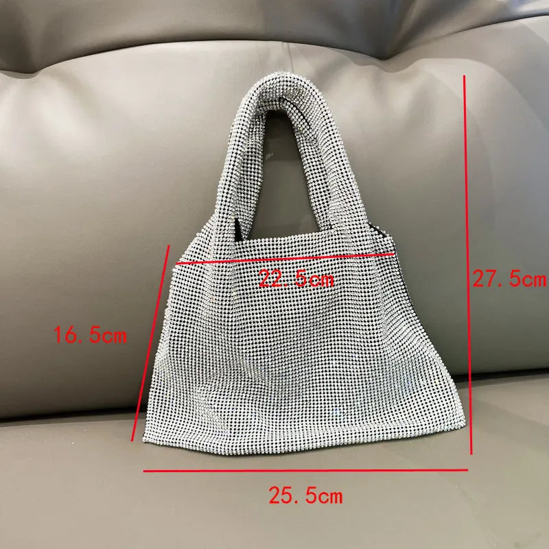 Silver cotton thread evening clutch covered in shiny rhinestones with an open outer pocket and shoulder strap.