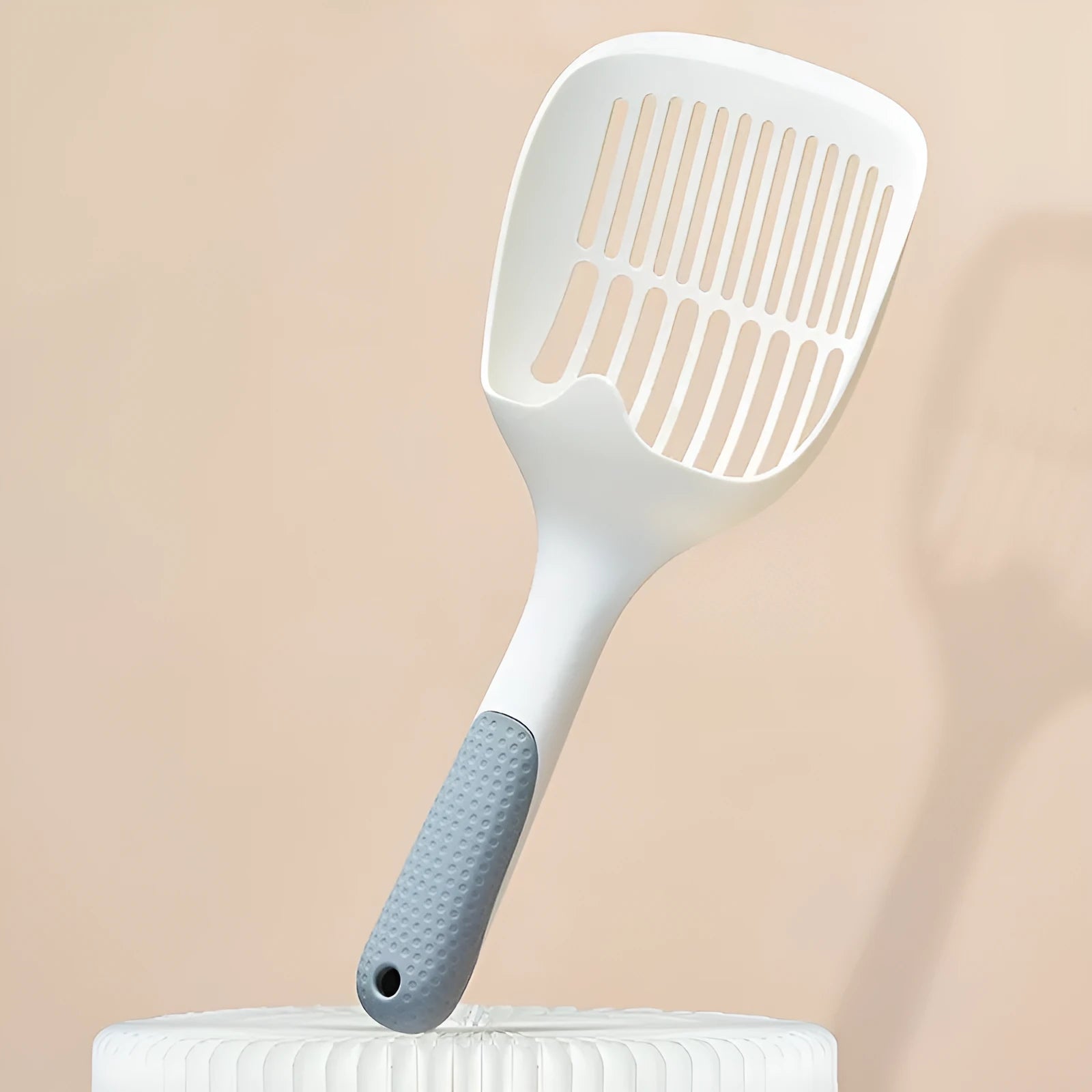 White plastic cat litter scoop with an attached rectangular base.