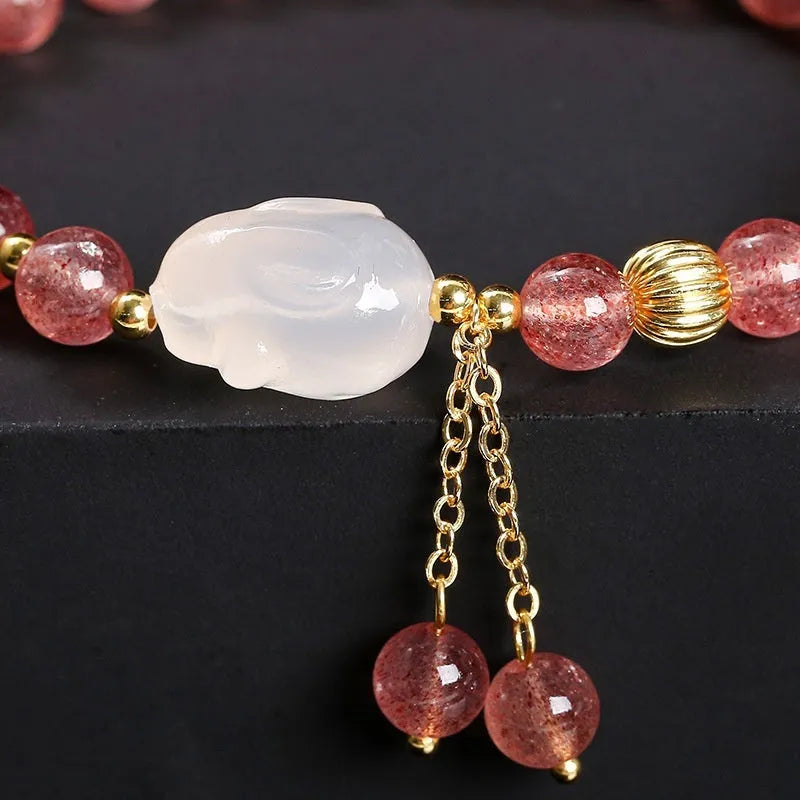Women's strawberry quartz and agate bracelet with 6mm round beads and a white rabbit charm pendant.