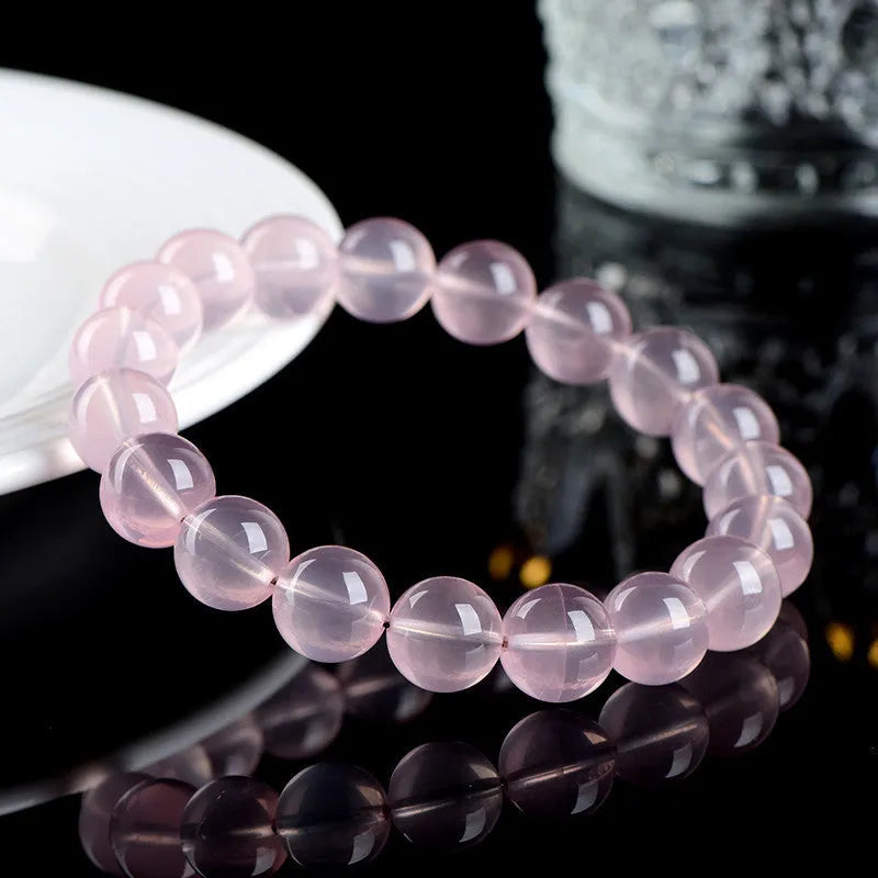 Natural starlight crystal round beads women's bracelet in pink on a wrist, showing polished single circle beads.