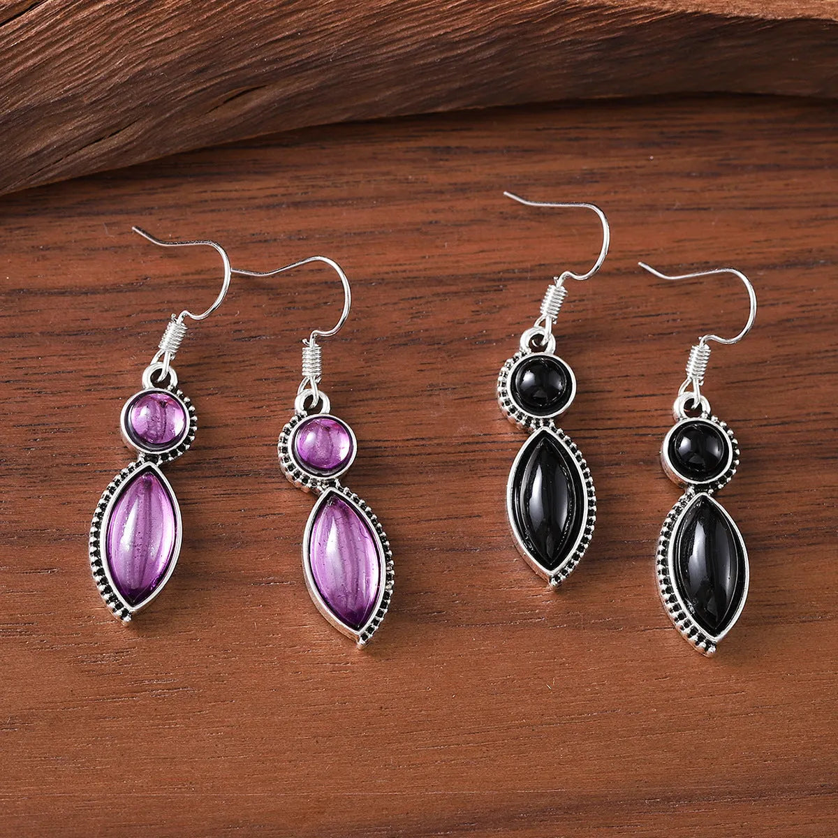 A pair of vintage geometric drop earrings with a round gemstone, in black and purple electroplated zinc alloy.