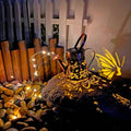 Iron solar garden lamp with a tapered butterfly silhouette emitting warm white light.