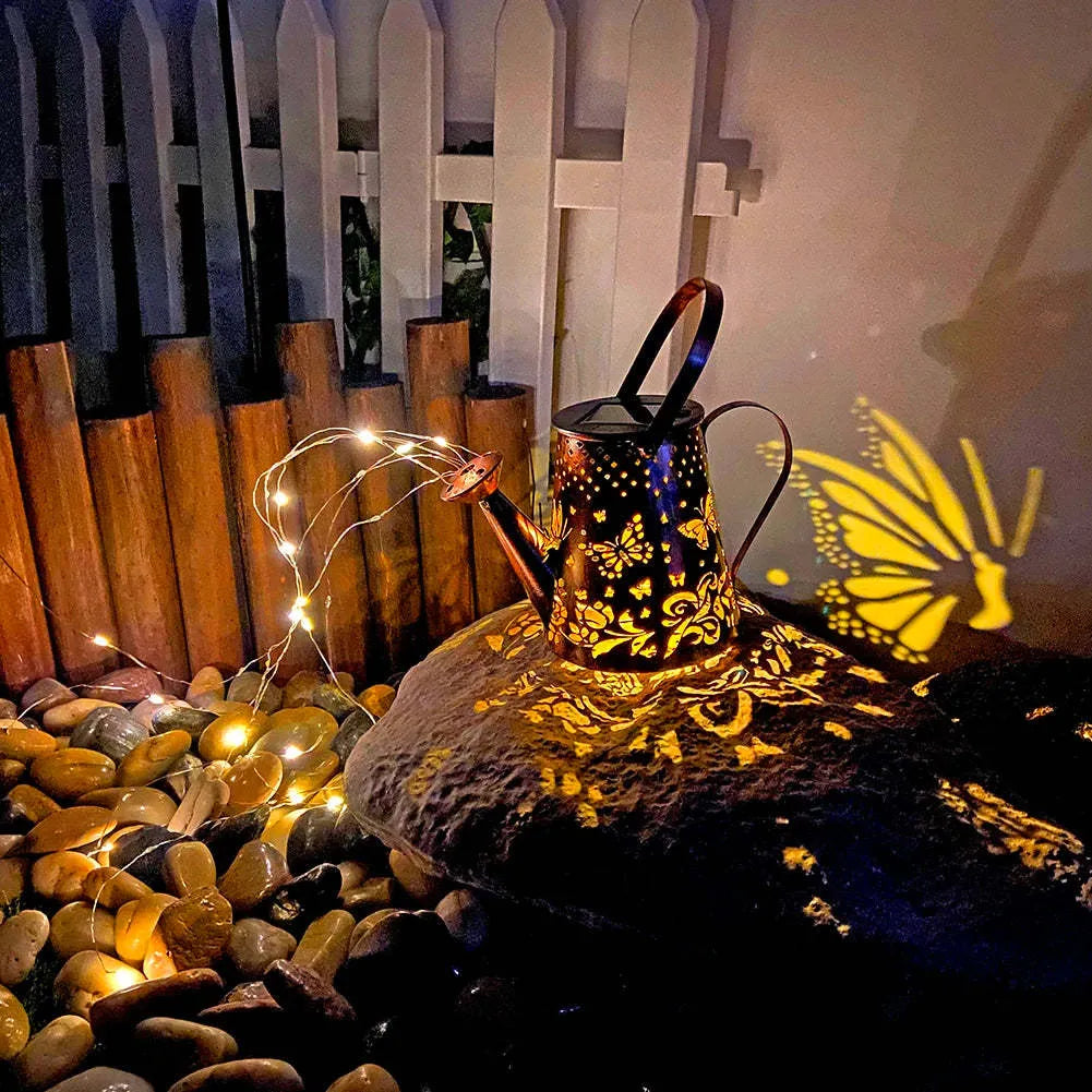 Iron solar garden lamp with a tapered butterfly silhouette emitting warm white light.