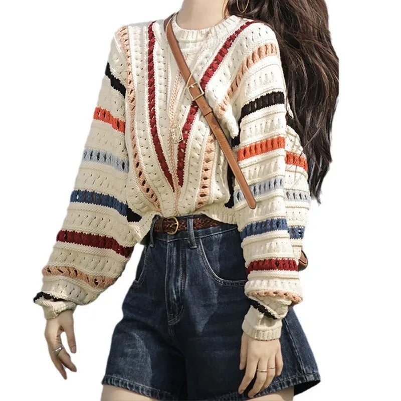 A woman's rainbow striped loose knit sweater with batwing sleeves on a hanger.