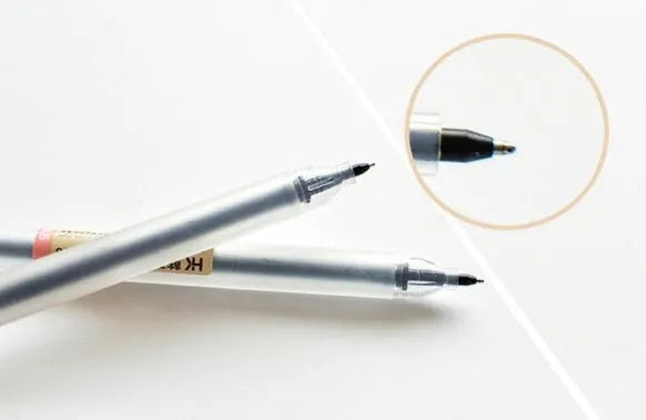 Pack of twelve black Muji 0.5mm gel pens with fine nibs, shown with pens uncapped.
