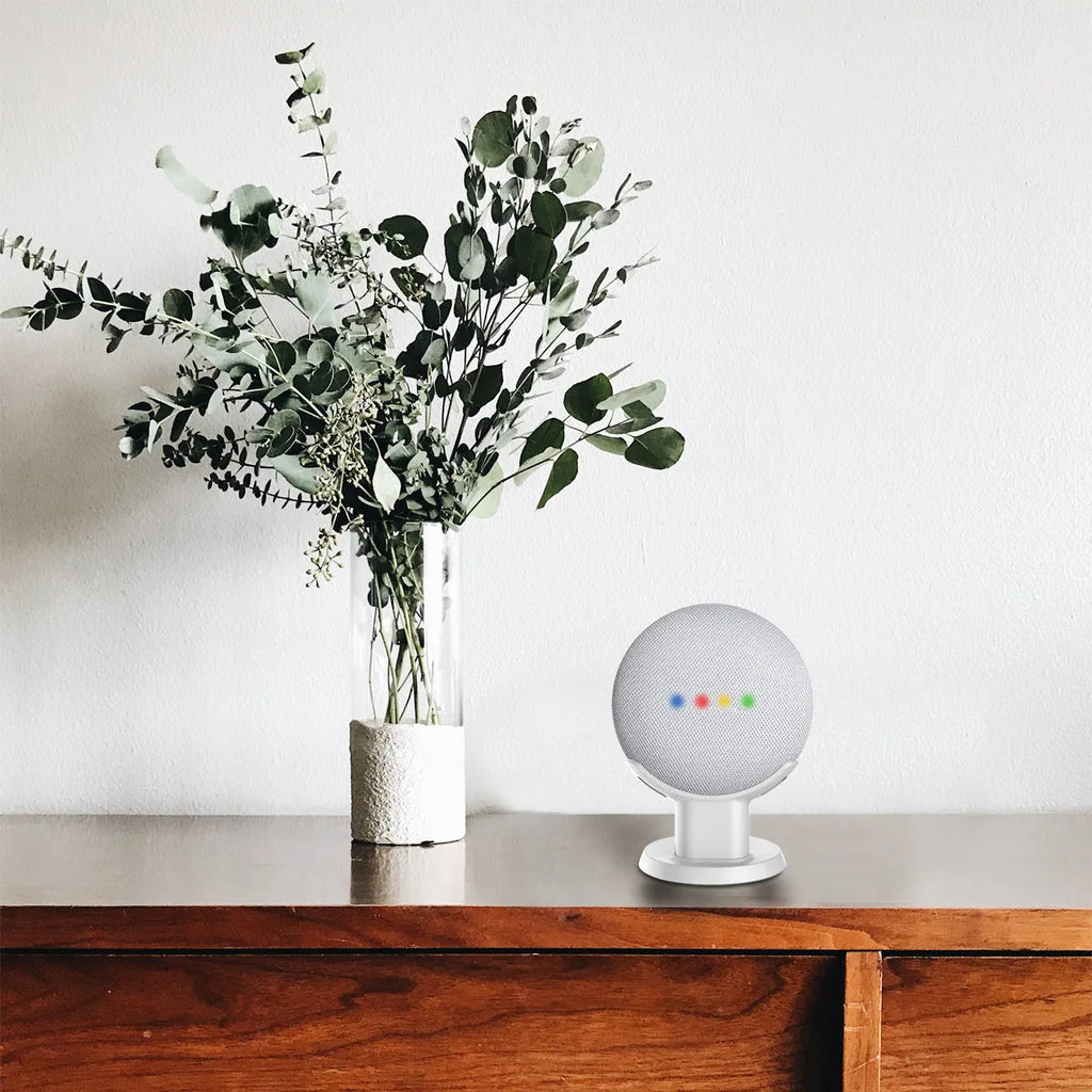 Black plastic stand holding a Google Home Mini smart speaker on a wooden table.