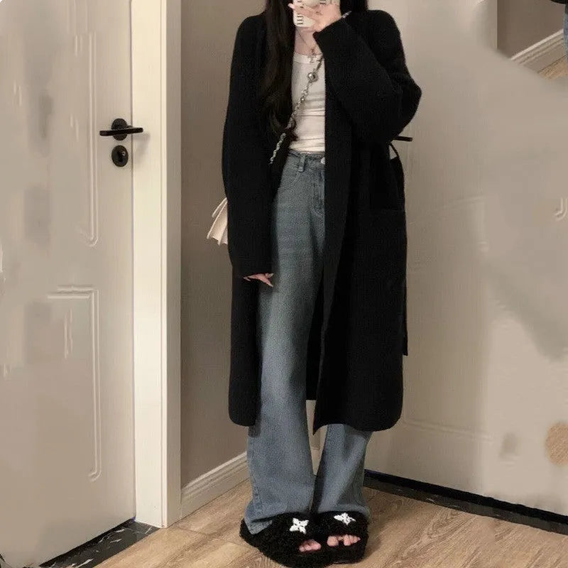 Dark grey loose knitted women's cardigan with a 3D pattern, shown open over a white top.