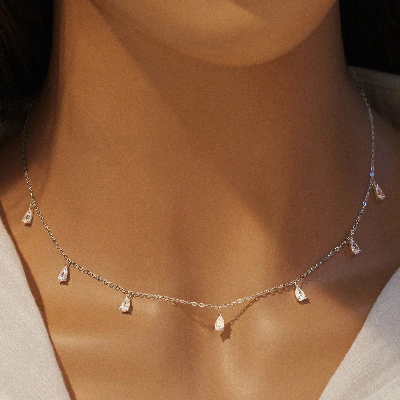 Silver necklace with a drop-shaped pendant holding a triangular zircon on an O-chain.