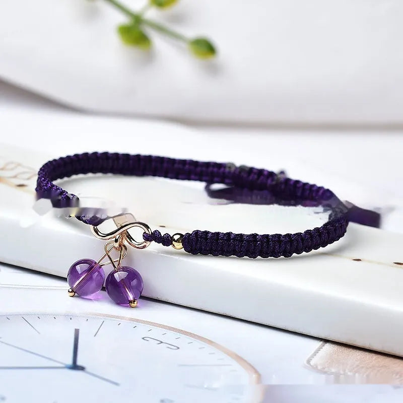 Women's bracelet with a natural strawberry quartz cherry charm on a black elasticated string.